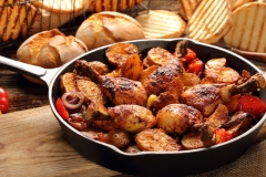 Roasted chicken legs with baked potato on frying pan