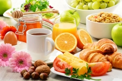 Breakfast consisting of fruits, orange juice, coffee, honey, bread and egg. Balanced diet